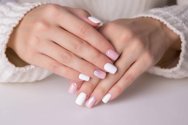 Female hands with pink and silver manicure nails Beautiful female hands with pink and silver manicure nails on white background gel nail polish stock pictures, royalty-free photos & images